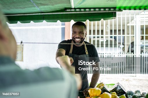 istock Salesman greeting the customer on a street market 1460371051