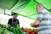 Salesman looking his customer choosing vegetables on a street market