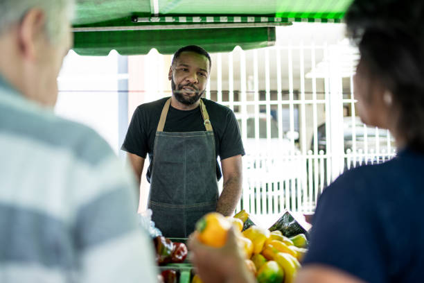 istock Salesman talking with customers on a street market 1460371069