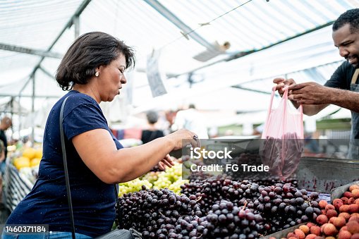 istock Customer choosing the grapes and giving to salesman on a street market 1460371184