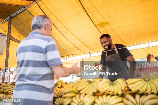 istock Salesman looking to his customer holding a bowl on a street market 1460371328