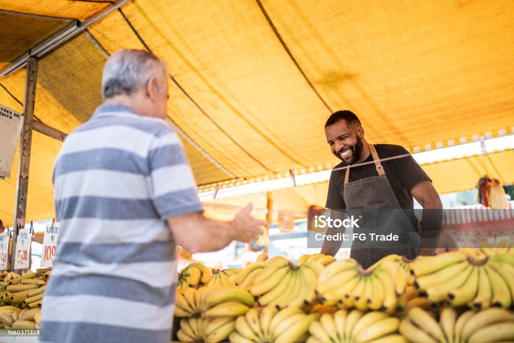 Salesman looking to his customer holding a bowl on a street market 30-34 Years Stock Photo