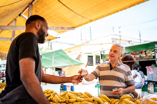 Customer paying the salesman for the fruits on a street market