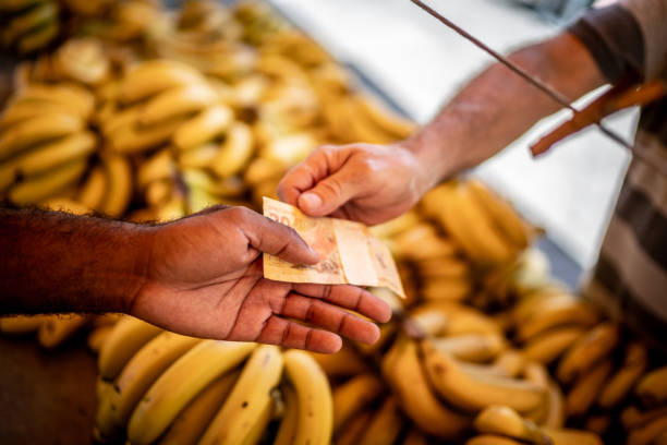 nahaufnahme von menschenhänden, die auf einem straßenmarkt mit brasilianischer währung bezahlen - real food fotos stock-fotos und bilder