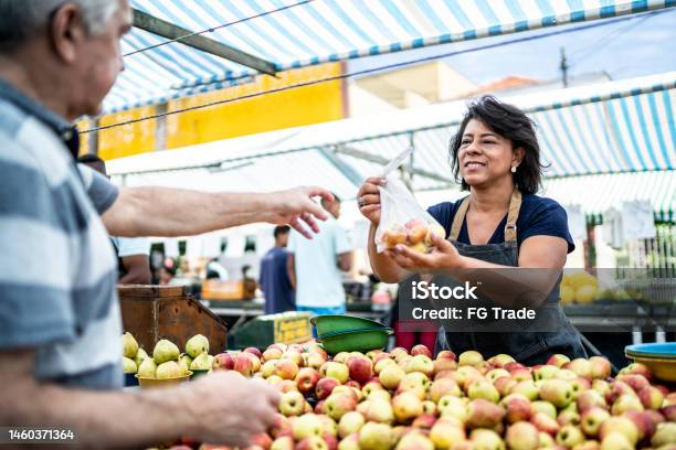 Saleswoman Giving The Fruits Bag To Her Customer On A Street Market Stock Photo - Download Image Now