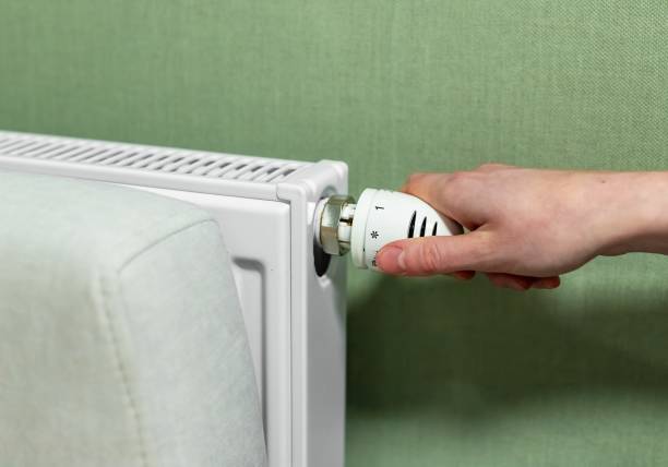 ラジエーターを手で調整し、オンまたはオフにします。寒い天候のコンセプトにおける家庭での熱、エネルギー消費