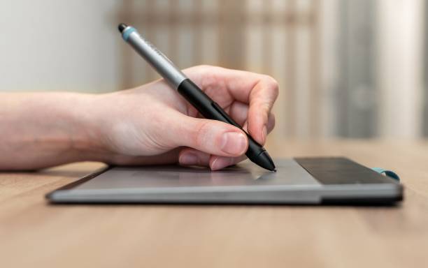 istock Digital artist hand holding stylus, drawing on tablet PC side view. Creative worker, designer sketching, using gadget and pen 1460381607
