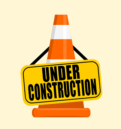 Under construction sign hanging on traffic safety cone