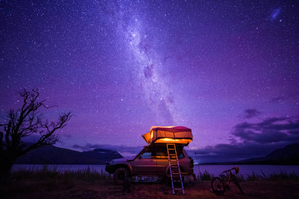 una autocaravana al caer la noche cerca del cuerpo de agua. - travel destinations fotos fotografías e imágenes de stock