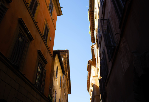 Looking up in between a narrow street in Rome