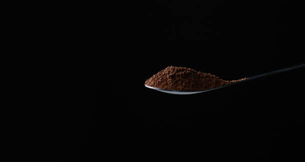 istock Raw of grinding cocoa or coffee on tea spoon for making drinking cup or bakery with black background 1460400372