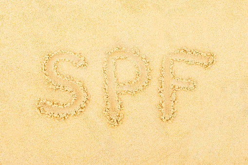 The inscription on the sand SPF. The concept of applying sunscreen during a beach holiday.