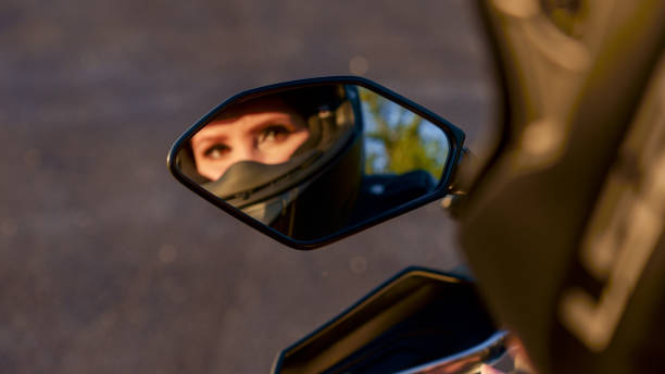 la fille sur une moto. reflet flou dans le miroir. focalisation sélective. montrer des filles dans le rétroviseur de la moto. très beaux yeux. - motorcycle mirror biker glove photos et images de collection