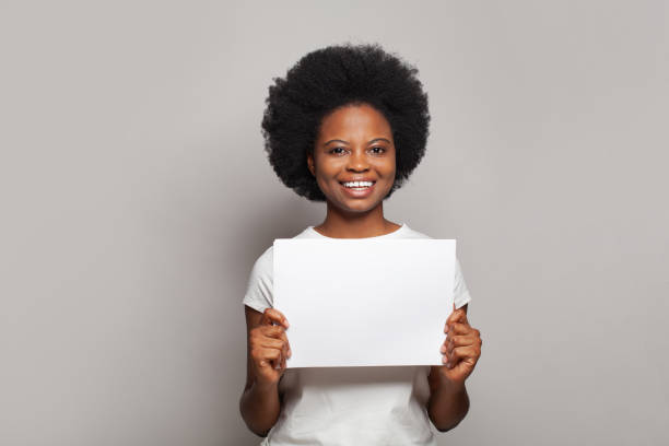 istock Confident woman smiling and showing white empty paper banner on white background 1460418383