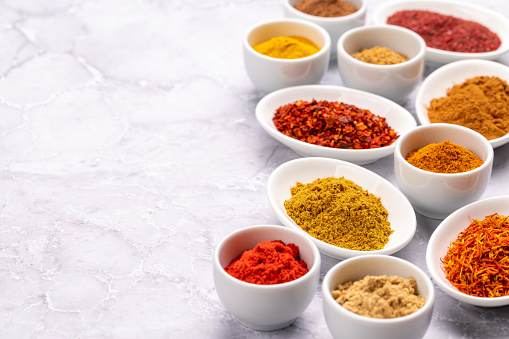 Various dried spices in small bowls on stone table