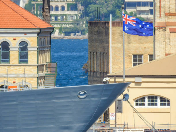 HMAS Warramunga National Flag Bow of HMAS Warramunga, a frigate of the Royal Australian Navy, flying the Australian flag.  She is docked at Garden Island Naval Base in Sydney Harbour.  In the background are historical buildings of Garden Island.  Across the harbour are residential buildings of Point Piper, some of the most expensive in Australia.  This image was taken from Mrs Macquarie's Chair on a sunny and windy afternoon on 28 January 2023. australian navy stock pictures, royalty-free photos & images