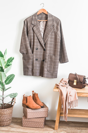 Checkered jacket in english style, red leather chelsea, cashmere scarf, leather bag in the interior of the room in scandinavian style