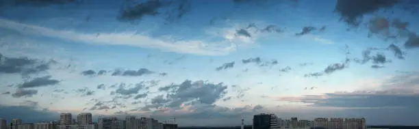 Blue sky panorama with clouds over tops of buildings