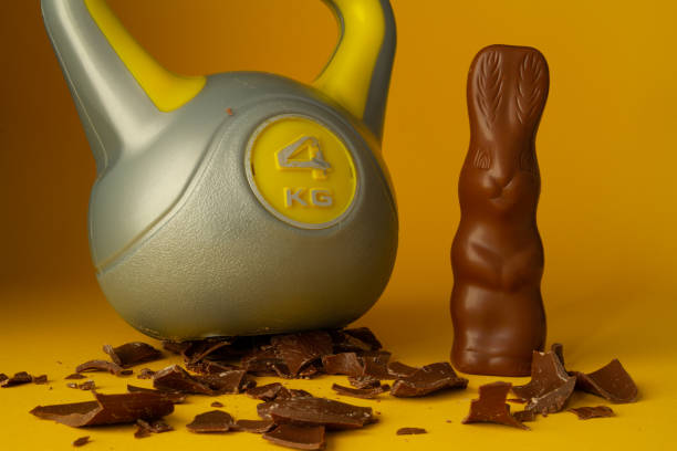 istock Heavy gym kettlebell crushing Easter chocolate eggs and bunny on wooden table. 1460436356