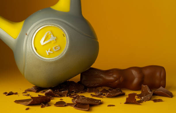 Easter composition, heavy kettlebell crushing chocolate bunny candy. Healthy fitness lifestyle, gym workout and fit training concept. Cheat day temptation vs sticking to diet.