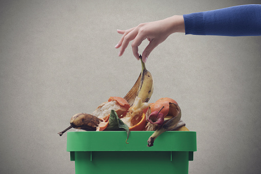 Woman putting organic biodegradable waste in a recycling bin, separate waste collection concept