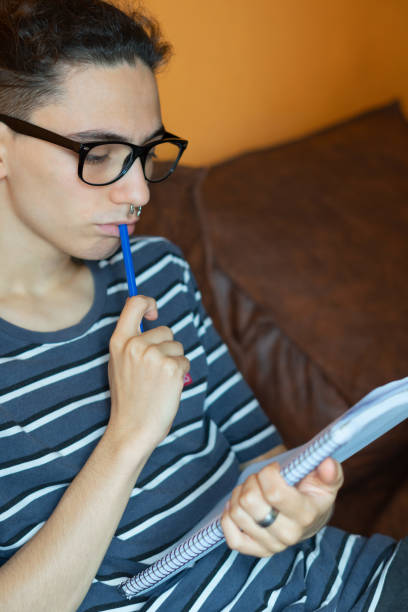 istock young male with glasses on the couch thinking what to write in his copybook 1460447664
