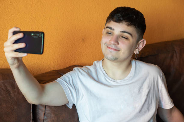 istock young man taking a selfie on the couch 1460447666