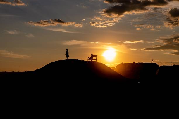 istock Silhouette of two people on a hill during an orange sunset 1460447677