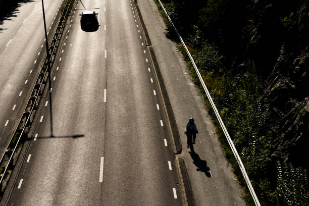 高速道路のそばの自転車道で孤独なサイクリスト.. - single line yellow road asphalt ストックフォトと画像