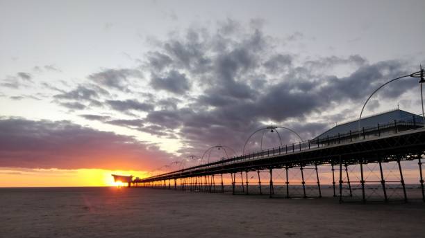 istock Beautiful view of a sunset and dramatic clouds at a beach with a pier 1460448324