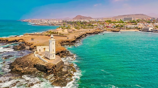 An aerial view of the shore of Praia de Santiago and the Praia lighthouse on a sunny day