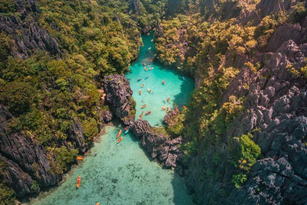 vue aérienne de touristes entrant dans le petit lagon de l’île de maniloc, el nido, palawan, philippines - palawan photos et images de collection