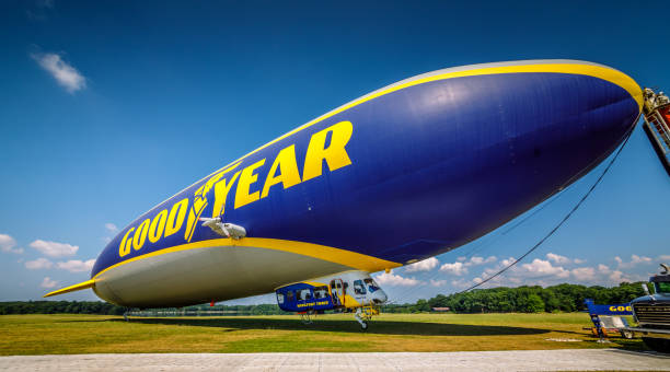 foto em close-up de um dirigível azul goodyear ancorado perto do campo - goodyear brand name - fotografias e filmes do acervo