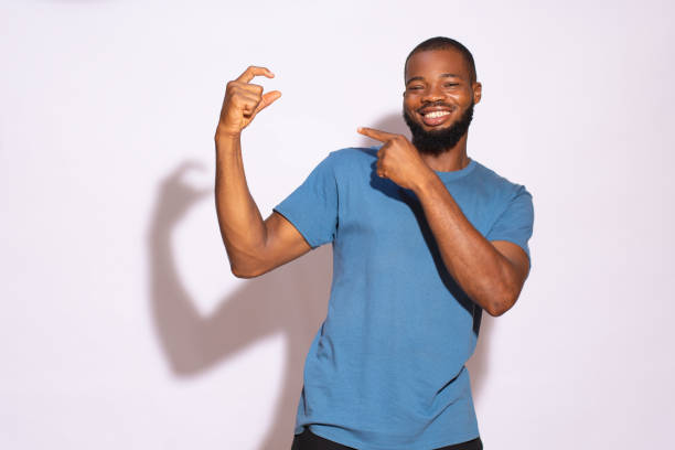 istock Black man with a blue t-shirt smiling and holding a copy space with hands on a white background. 1460450164