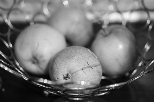 A grayscale shot of apples in a metal bowl