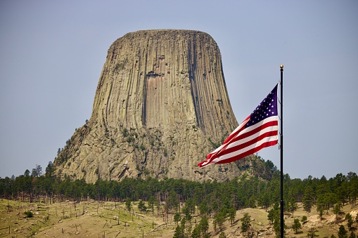 A scenic view of the Devils Tower National Monument and the flag of the USA
