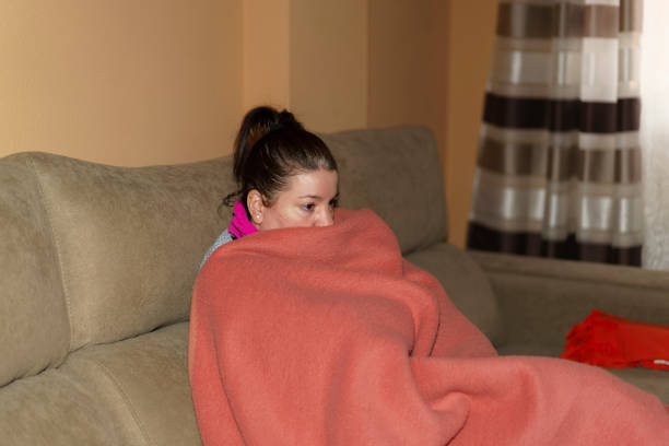 istock Woman sitting on the sofa wrapped in a blanket 1460452591