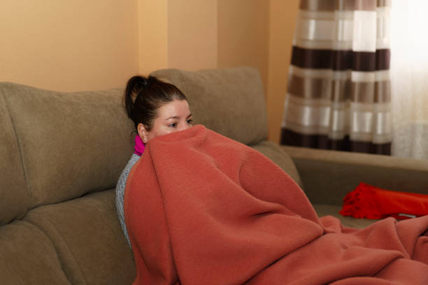 istock Woman sitting on the sofa wrapped in a blanket 1460452607