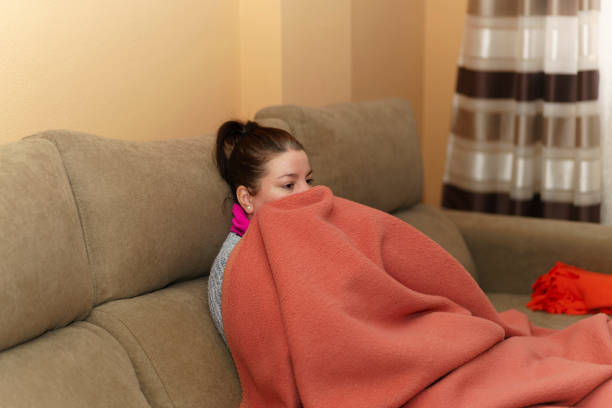 istock Woman sitting on the sofa wrapped in a blanket 1460452658