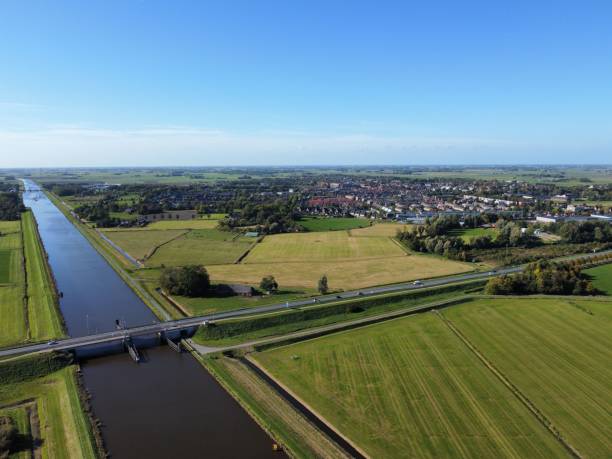 istock Aerial view of long highway stretching above a river and vast open fields under blue sky 1460452672