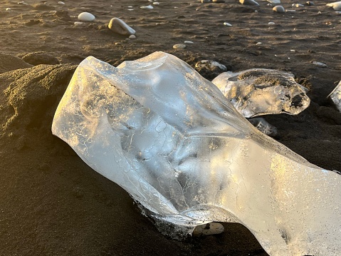 A closuep of a large piece of ice on the wet sandy ground