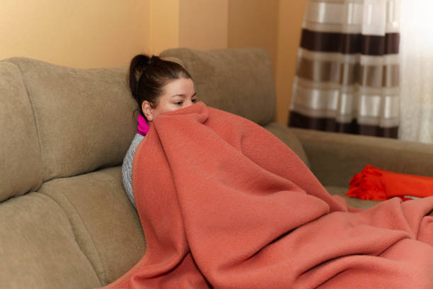 istock Woman sitting on the sofa wrapped in a blanket 1460453284