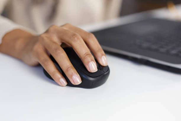 istock BIPOC woman works on computer in an office. Black female clicking with wireless computer mouse in closeup 1460455161