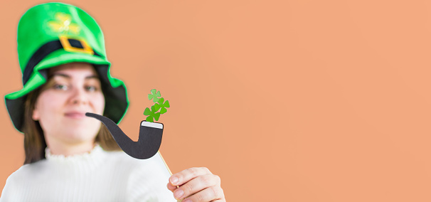 Portrait of man wearing green wig and hat for St. Patrick's day with clover leaves on white background. He's showing two thumbs up.