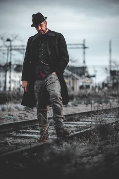 istock Stylish man in a long black coat and a hat with the blurred background 1460456212