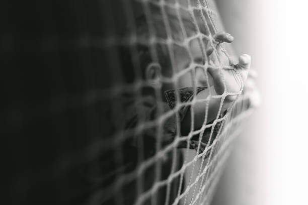 istock Boy looks through a football goal 1460456843