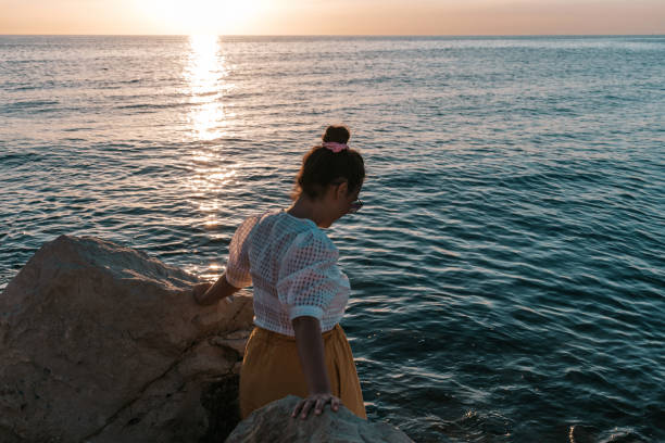 istock Caucasian female standing in between two big rocks at the coast 1460461031
