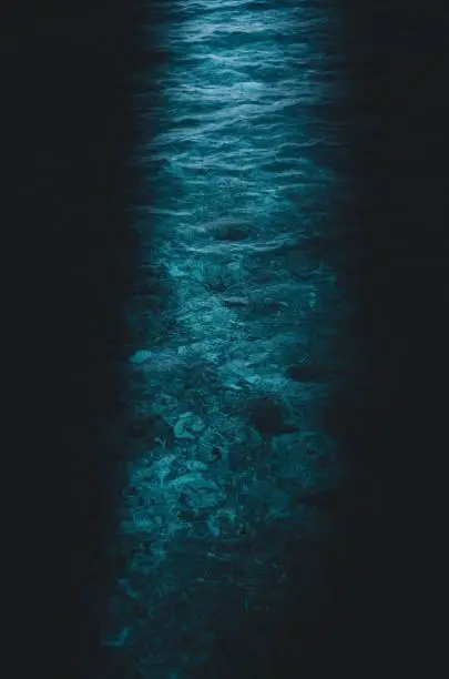 Vertical shot of the blue light shimmering through a cave entrance onto the water