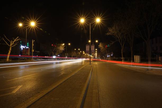 istock Night view of empty asphalt road with illuminating lamp posts and trees 1460465792