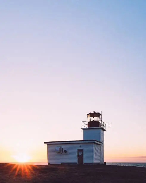 A vertical shot of a lightstation by the coast at sunset